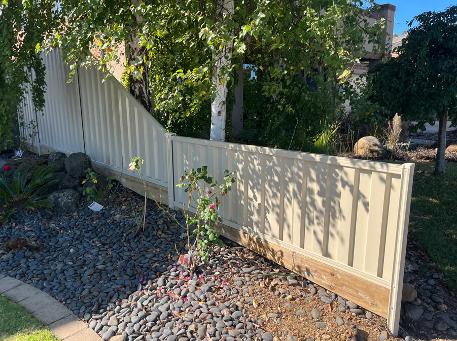 Paperbark Colorbond front boundary fencing installed on a sloping block. Paperbark Colorbond front fencing completed as a timber fence replacement for an existing property in Berwick, featuring stepped panels to suit the sloping site.