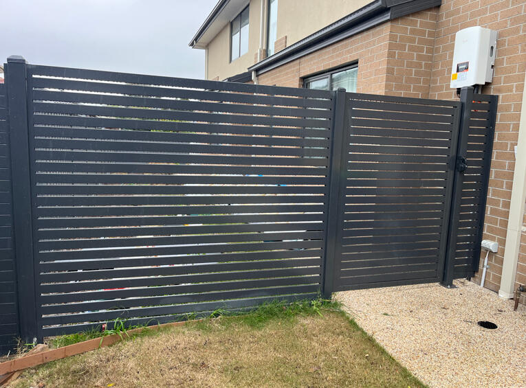 Black vertical aluminium slat gate and side privacy fence installed for a modern new home. 1.8m high black aluminium slat privacy fence and premium side gate completed for a modern home in Cranbourne North