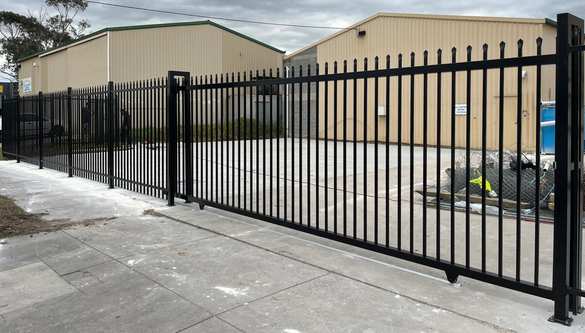 Black commercial sliding gates and spear-top steel security fence installed at a factory in Seaford. Commercial security fencing project completed in Seaford featuring three 6m x 2.1m motorised sliding gates and 30m of matching spear-top steel fencing to prepare the property for sale.