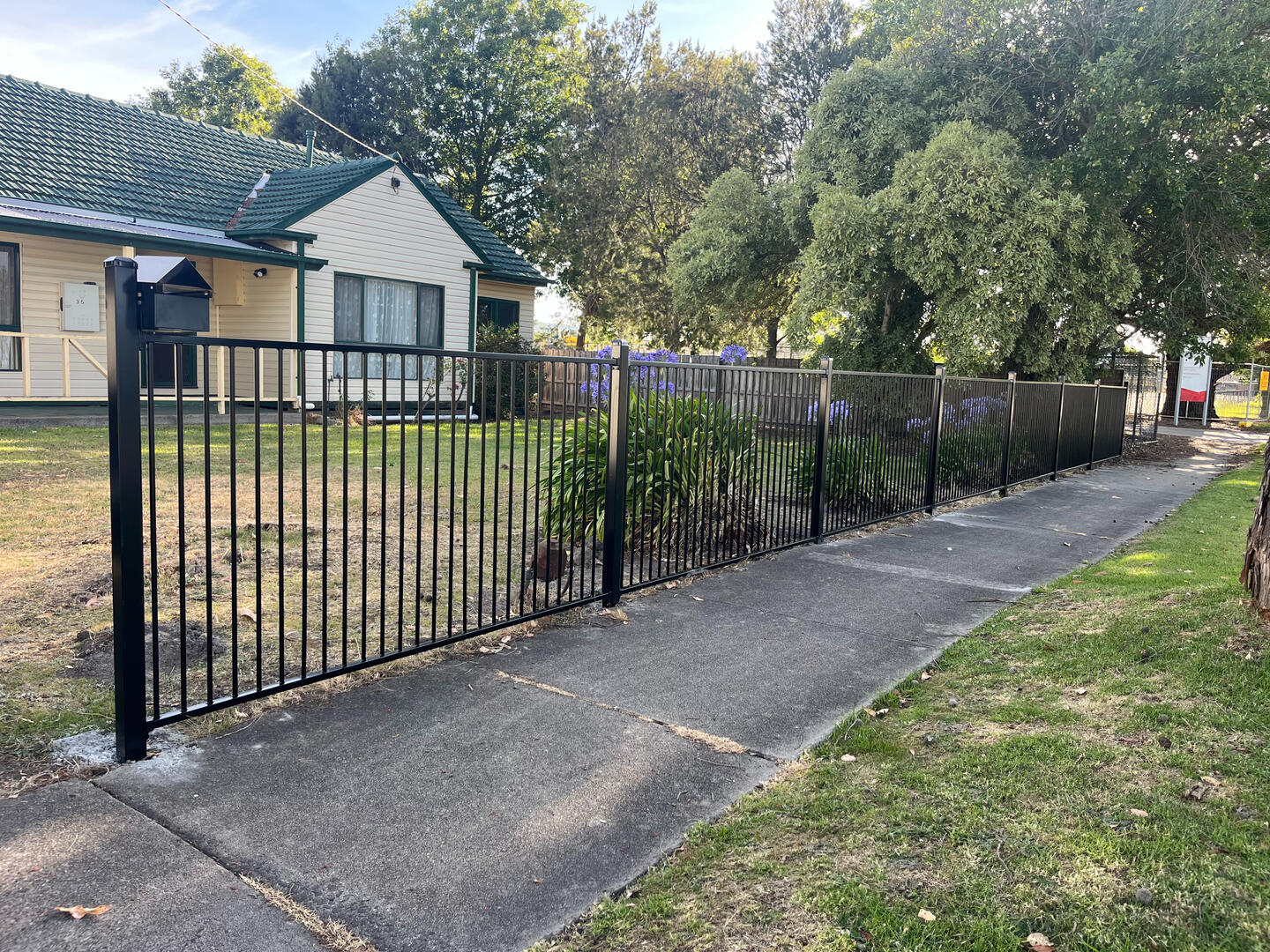 Flat top metal front fence installed to improve security at an older property in Narre Warren 1.2m high flat top metal front fencing completed in Narre Warren to improve residential security, define the property boundary and modernise the appearance of an older home.