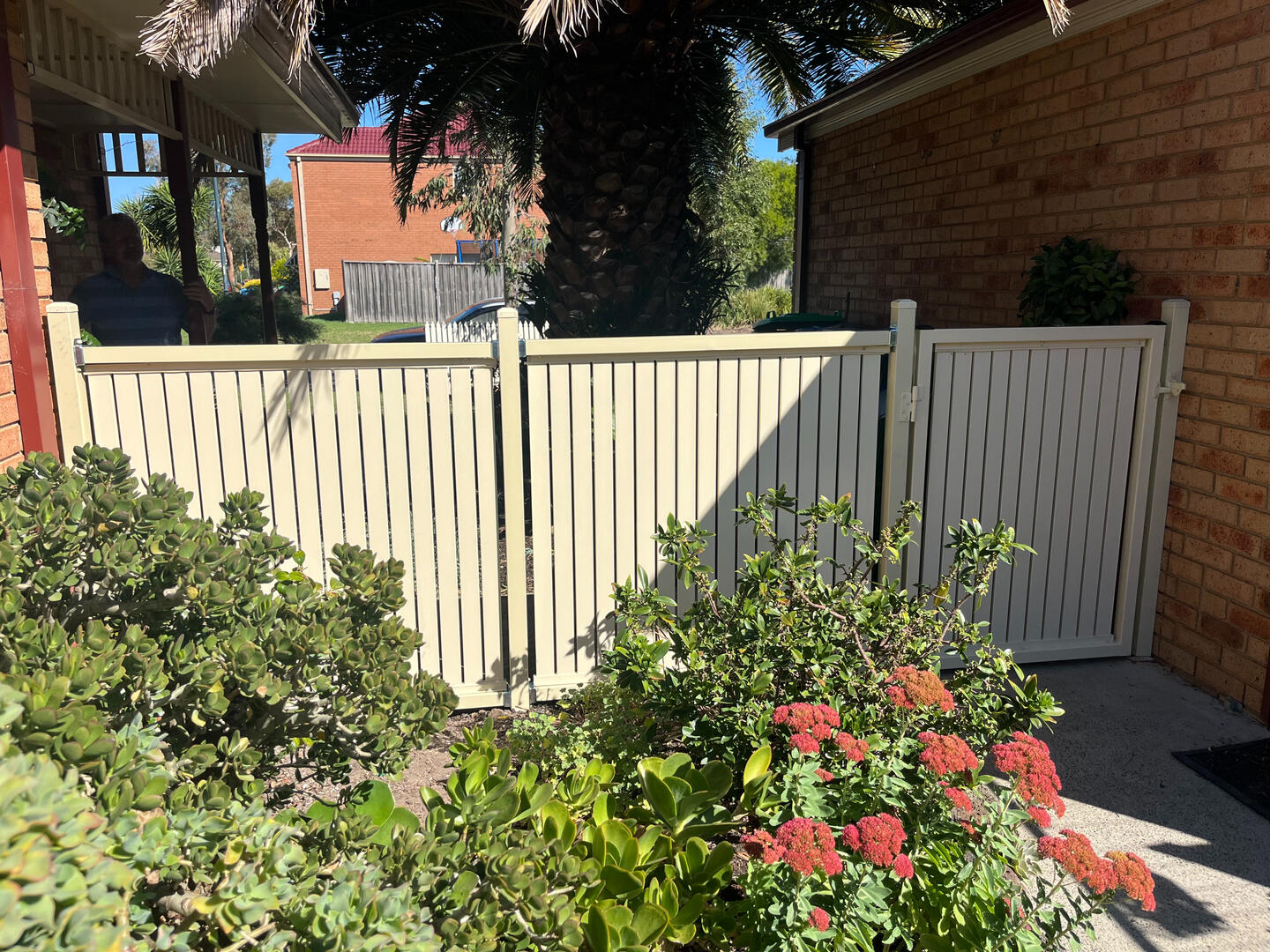 Custom aluminium slat garden fence and pedestrian gate completed in Lynbrook featuring vertical slats, 10mm gaps and a modern cream powder-coated finish for secure outdoor access.