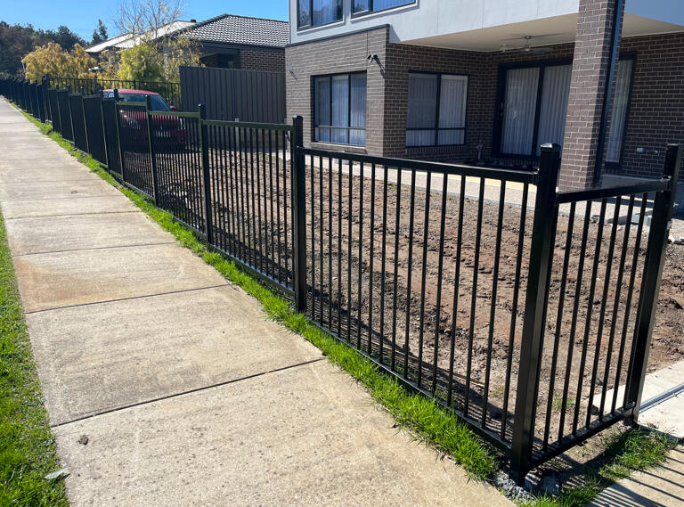 Stepped flat top metal fencing installed beside a footpath in Pakenham. 1.2m high stepped flat top metal fencing completed in Pakenham to define the property boundary beside a public footpath while enhancing street appeal and safety.